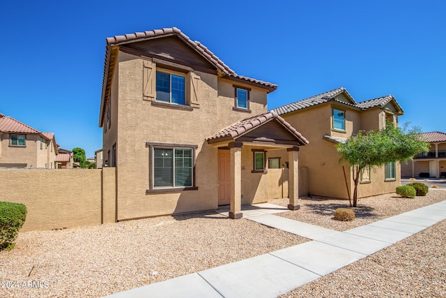 mediterranean / spanish house with a tile roof, stucco siding, and fence