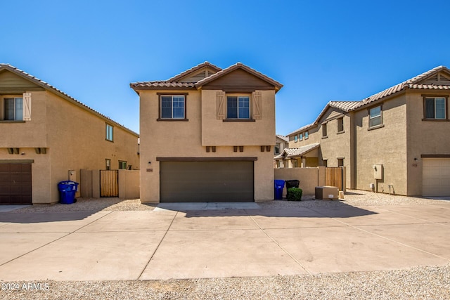 view of front of home with driveway, fence, a tiled roof, a garage, and stucco siding
