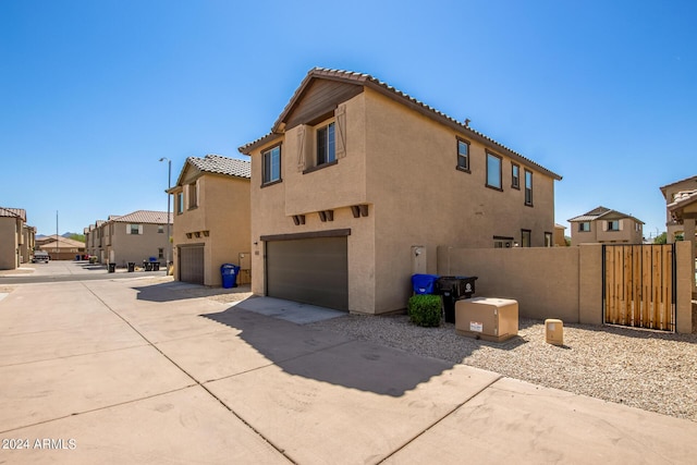 view of home's exterior with a tiled roof, an attached garage, concrete driveway, a residential view, and stucco siding