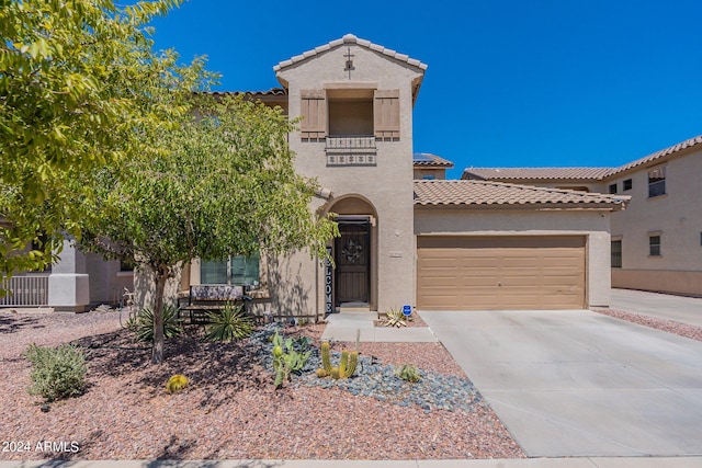 mediterranean / spanish-style house with a garage, concrete driveway, a tiled roof, and stucco siding