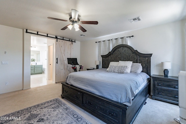 carpeted bedroom featuring a barn door, ensuite bath, and ceiling fan