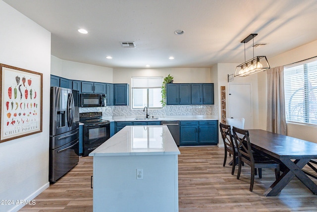 kitchen with light wood-type flooring, black appliances, sink, and a healthy amount of sunlight