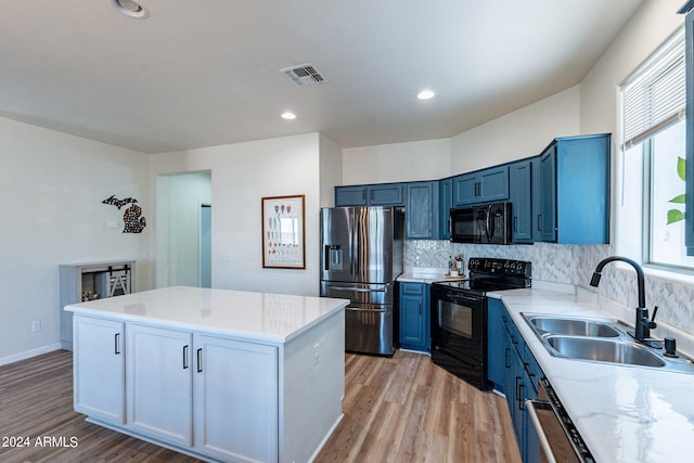 kitchen featuring backsplash, blue cabinetry, light hardwood / wood-style flooring, sink, and black appliances