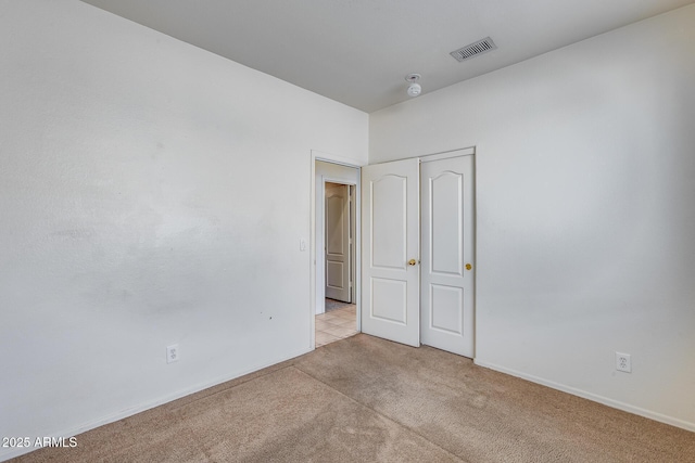 unfurnished bedroom with baseboards, visible vents, a closet, and light colored carpet