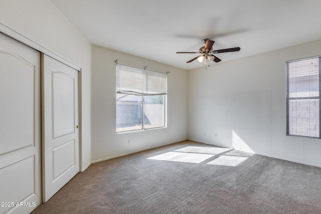 unfurnished bedroom featuring a ceiling fan, a closet, and light colored carpet