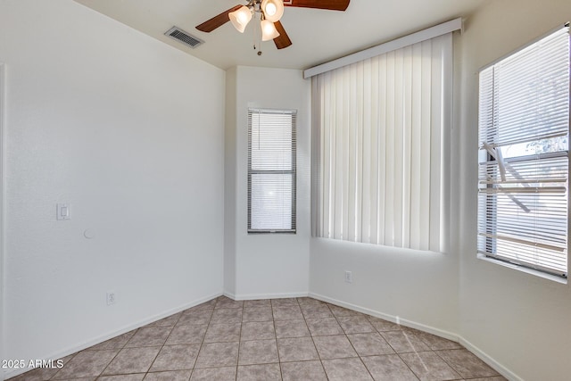 spare room featuring light tile patterned floors, ceiling fan, visible vents, and baseboards