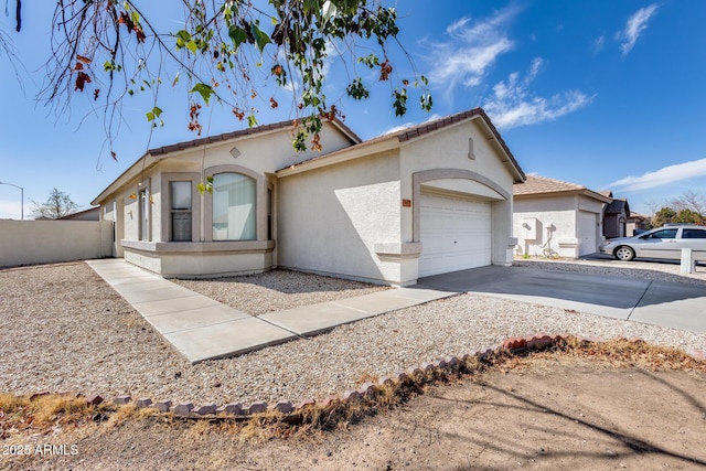 view of front of home with stucco siding, concrete driveway, an attached garage, fence, and a tiled roof