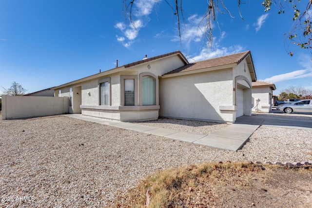 view of front of property with a garage, concrete driveway, fence, and stucco siding