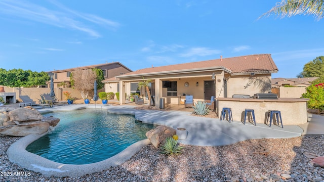 view of pool with a patio area, a bar, and an outdoor kitchen