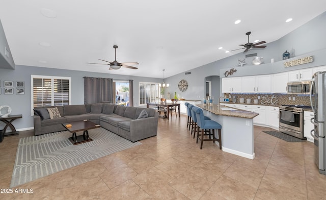 living room with ceiling fan, sink, lofted ceiling, and light tile patterned flooring