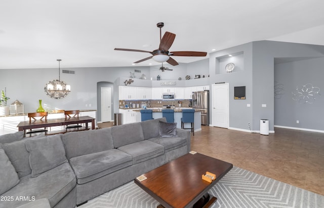 living room with vaulted ceiling and ceiling fan with notable chandelier