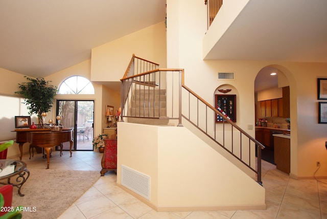 staircase featuring tile patterned floors and high vaulted ceiling