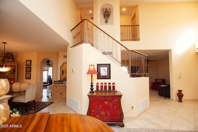 staircase with tile patterned flooring, a towering ceiling, and ceiling fan