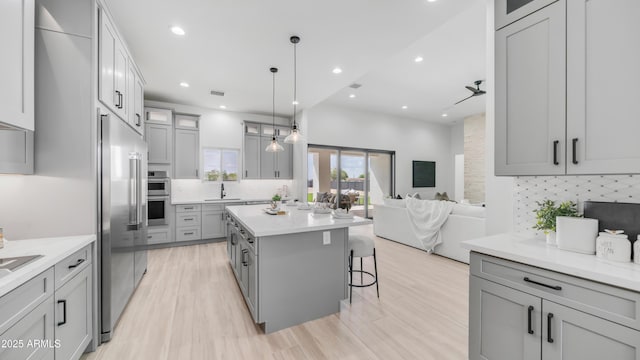 25916 S 198th St, Queen Creek, AZ 85142 - kitchen with light wood finished floors, a kitchen breakfast bar, stainless steel appliances, tasteful backsplash, and gray cabinets
