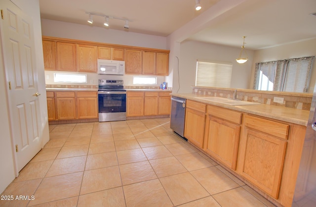 kitchen with decorative light fixtures, appliances with stainless steel finishes, light tile patterned floors, and sink