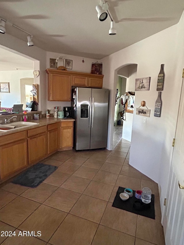 kitchen with sink, stainless steel fridge with ice dispenser, track lighting, and light tile patterned flooring