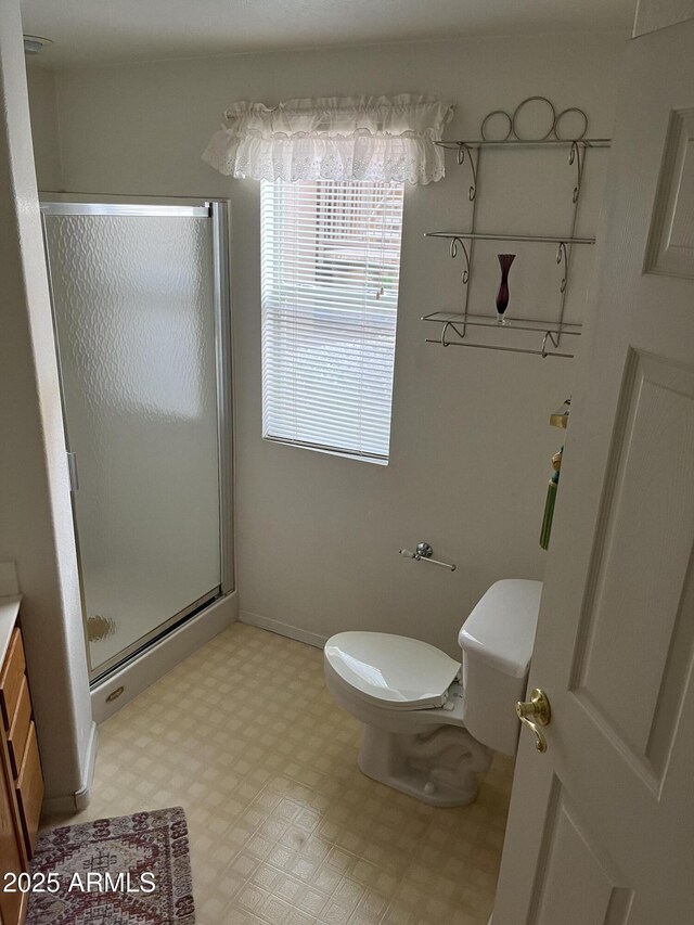 bathroom with toilet, vanity, baseboards, a shower stall, and tile patterned floors