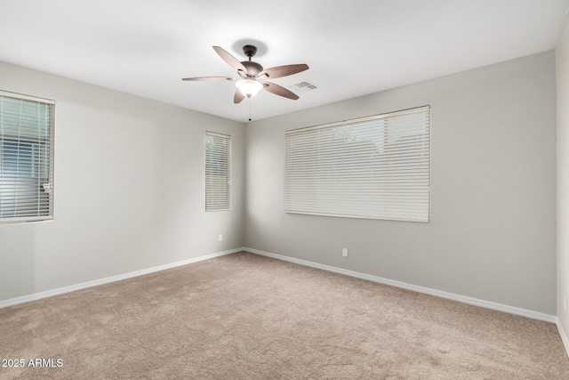 carpeted spare room with baseboards, visible vents, and ceiling fan