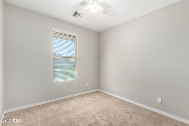 empty room with light colored carpet, baseboards, visible vents, and ceiling fan