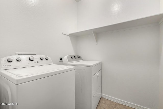 clothes washing area featuring washer and clothes dryer, laundry area, baseboards, and light tile patterned floors