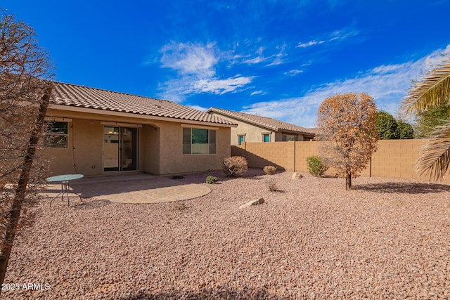 rear view of house featuring a patio area, stucco siding, a tiled roof, and a fenced backyard