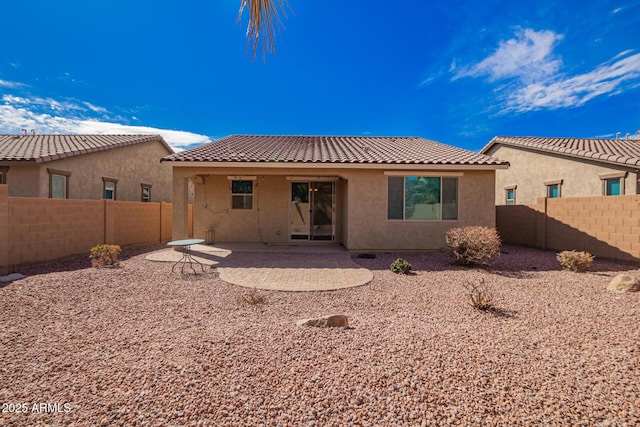 rear view of house featuring stucco siding, a patio area, a fenced backyard, and a tile roof