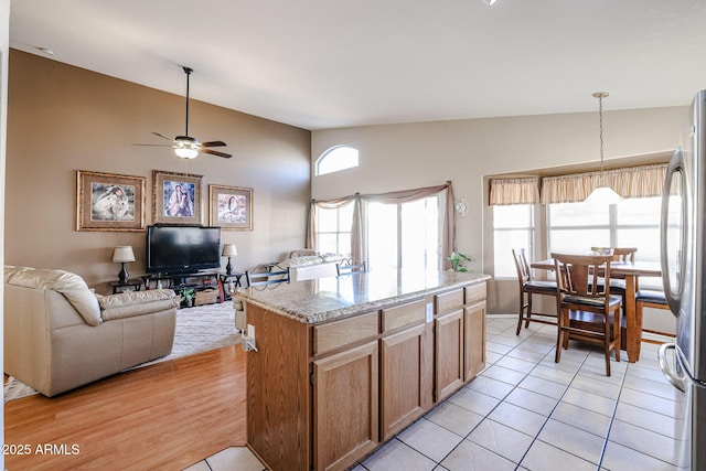 kitchen with decorative light fixtures, ceiling fan, vaulted ceiling, a center island, and stainless steel fridge