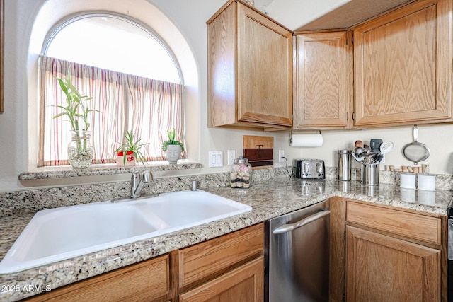 kitchen with stainless steel dishwasher, light stone counters, and sink