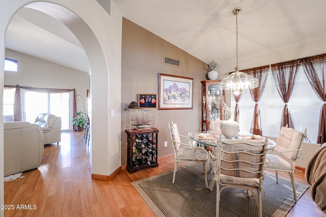 dining space with vaulted ceiling, a notable chandelier, and light hardwood / wood-style flooring