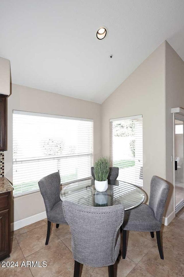 dining area featuring lofted ceiling and light tile patterned floors