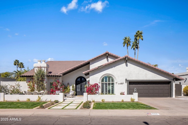 mediterranean / spanish-style house featuring a tile roof, concrete driveway, stucco siding, french doors, and a garage