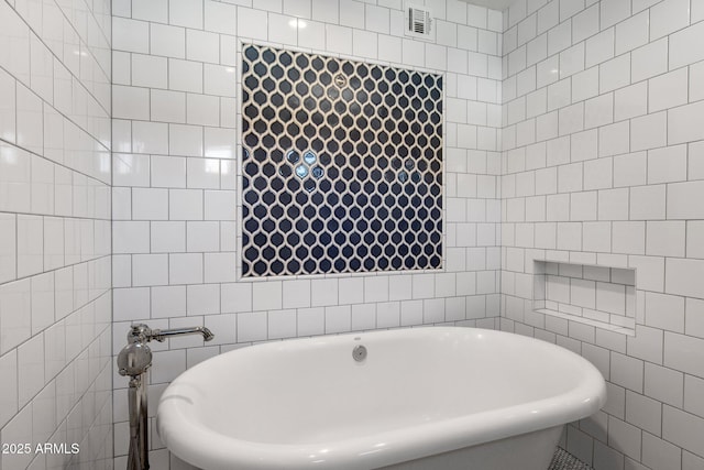 full bath featuring a soaking tub, tile walls, and visible vents