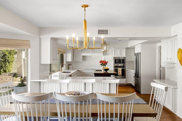 kitchen with visible vents, dark wood finished floors, decorative backsplash, appliances with stainless steel finishes, and a sink