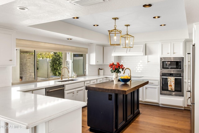 kitchen with wood finished floors, visible vents, a sink, stainless steel appliances, and wood counters