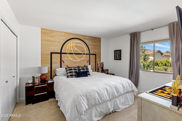 bedroom with a closet, wooden walls, an accent wall, and carpet