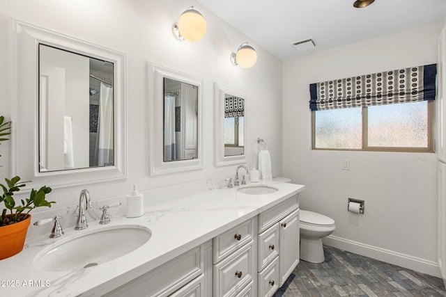 bathroom with double vanity, visible vents, baseboards, and a sink