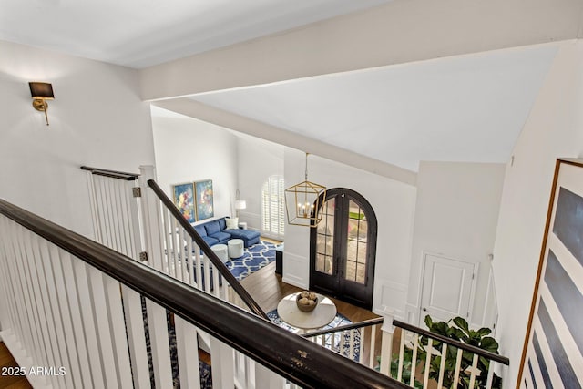 interior space featuring french doors, lofted ceiling, a notable chandelier, and wood finished floors