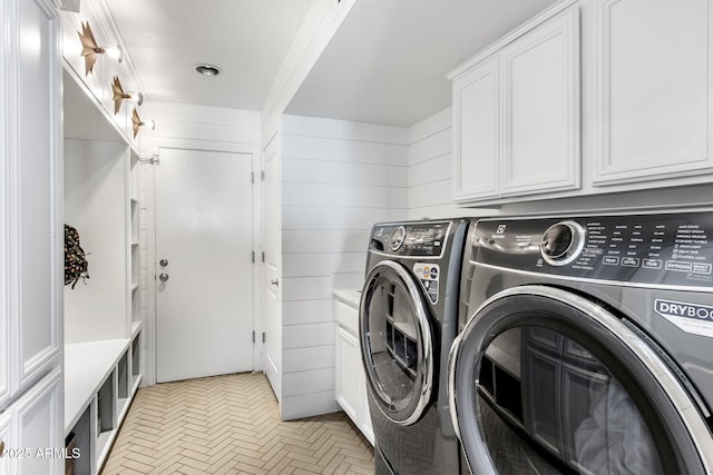 laundry room featuring washer and dryer, cabinet space, and wood walls