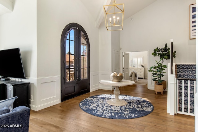 entryway featuring a wainscoted wall, arched walkways, an inviting chandelier, and wood finished floors