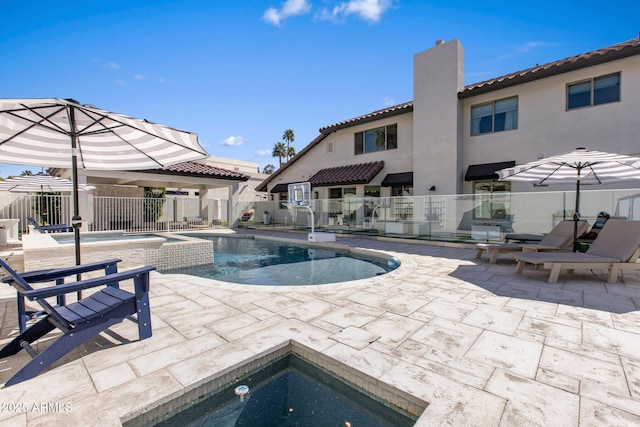 view of swimming pool with a patio area, a fenced in pool, fence, and an in ground hot tub