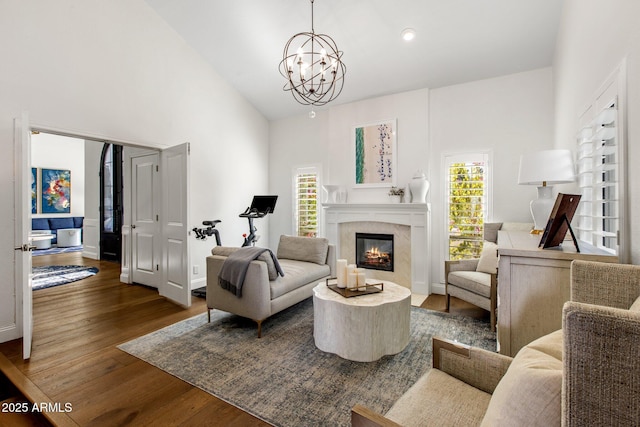 living area with dark wood finished floors, a healthy amount of sunlight, high vaulted ceiling, and a premium fireplace