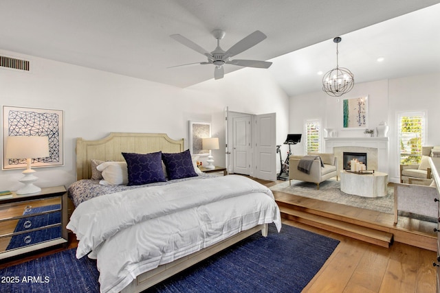 bedroom featuring hardwood / wood-style flooring, multiple windows, visible vents, and a premium fireplace