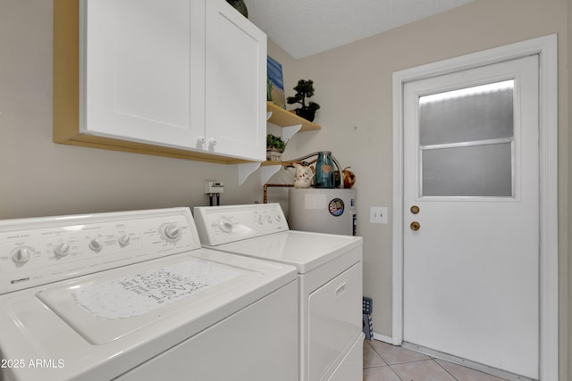 washroom featuring cabinets, electric water heater, a textured ceiling, washer and clothes dryer, and light tile patterned floors