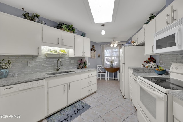 kitchen featuring a skylight, white cabinetry, sink, white appliances, and light tile patterned floors