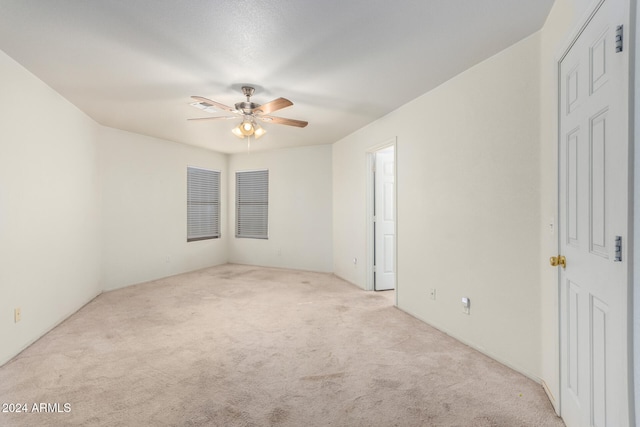 spare room featuring light colored carpet and ceiling fan