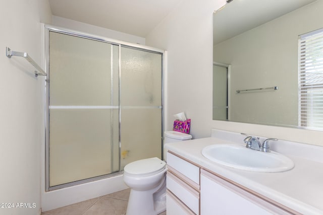 bathroom featuring tile patterned flooring, vanity, a shower with door, and toilet