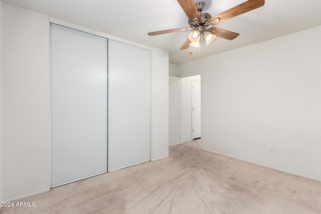 unfurnished bedroom with ceiling fan, a closet, and light carpet