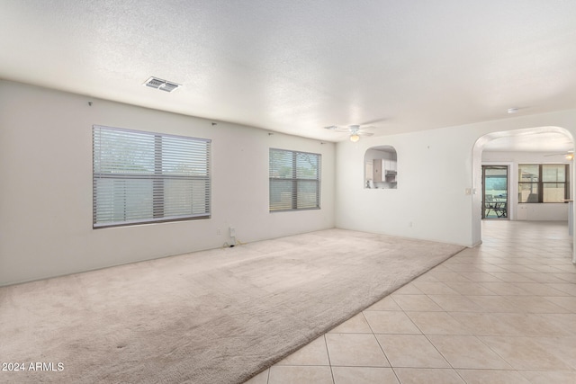 spare room featuring light carpet, a textured ceiling, and ceiling fan