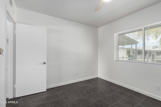 unfurnished room featuring visible vents, baseboards, ceiling fan, and dark tile patterned flooring