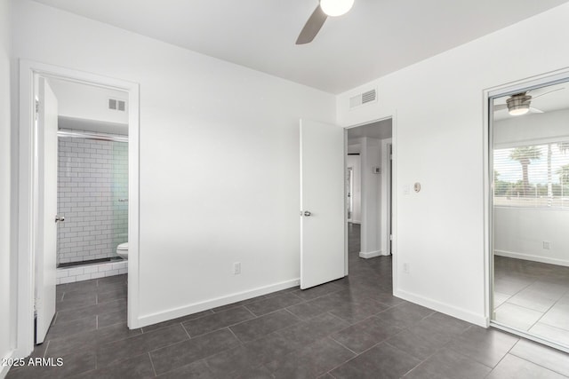 unfurnished bedroom with dark tile patterned floors, visible vents, connected bathroom, and baseboards